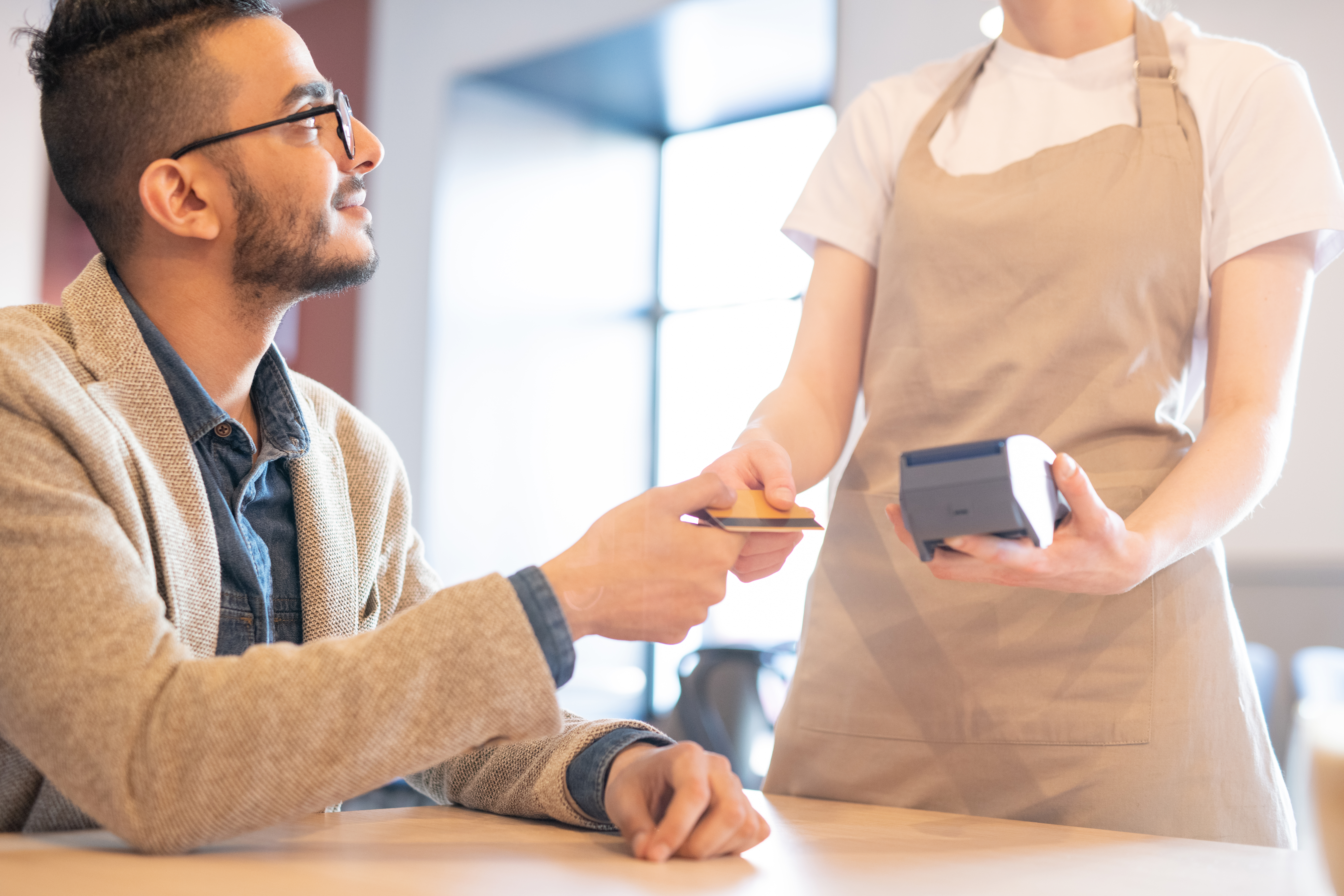 a man wearing business casual clothing hands a waitress his credit card